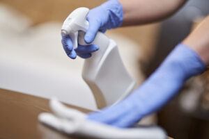 Maid disinfecting bedside table in the bedroom