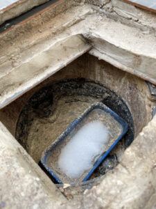 Grease trap plastic box with fatty water floating on top and chemical bubble